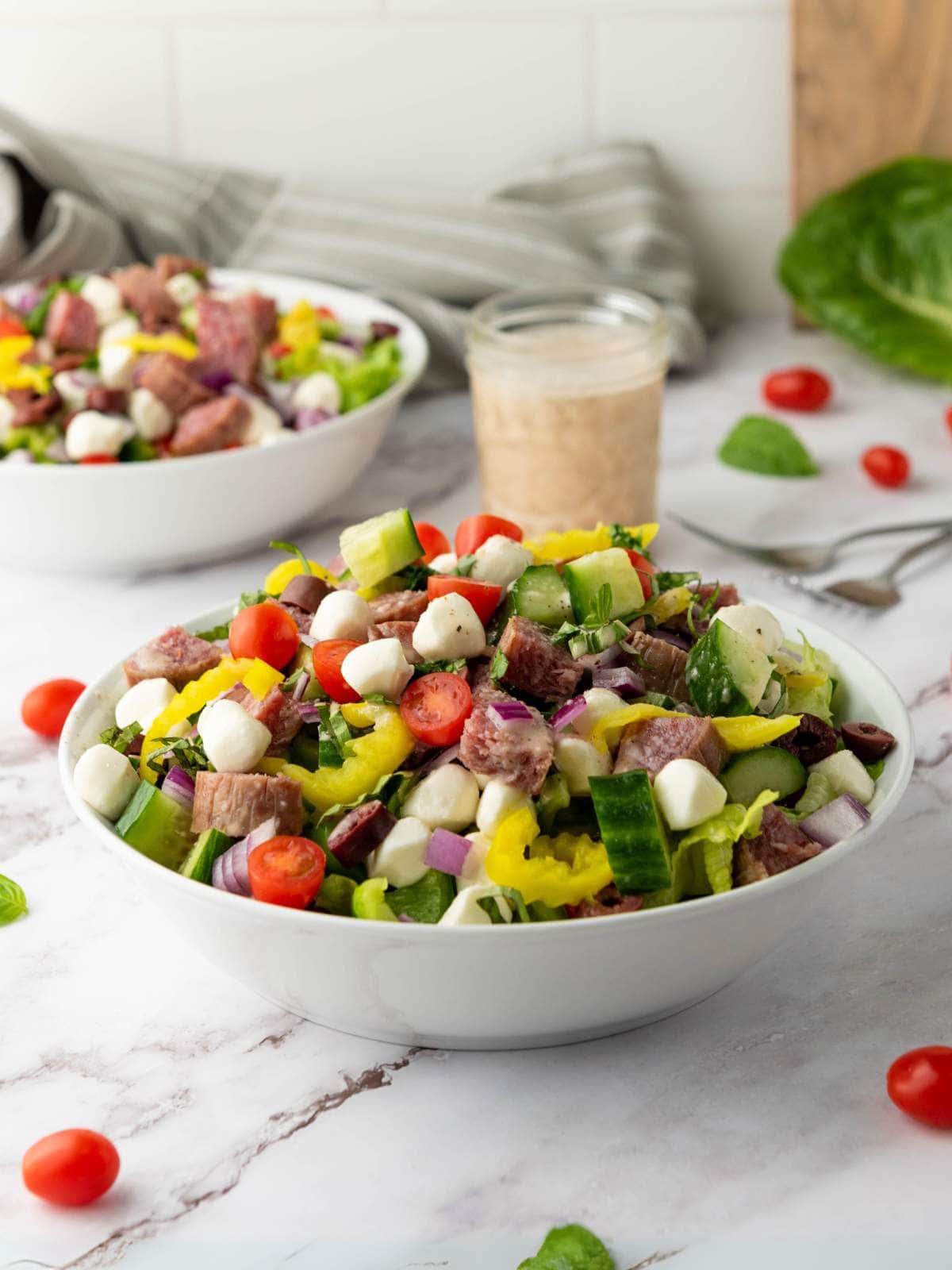 A bowl of italian salad with cucumbers and other ingredients.