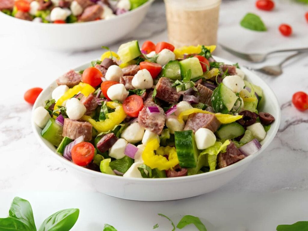 A bowl of italian salad with diced meat and other ingredients.