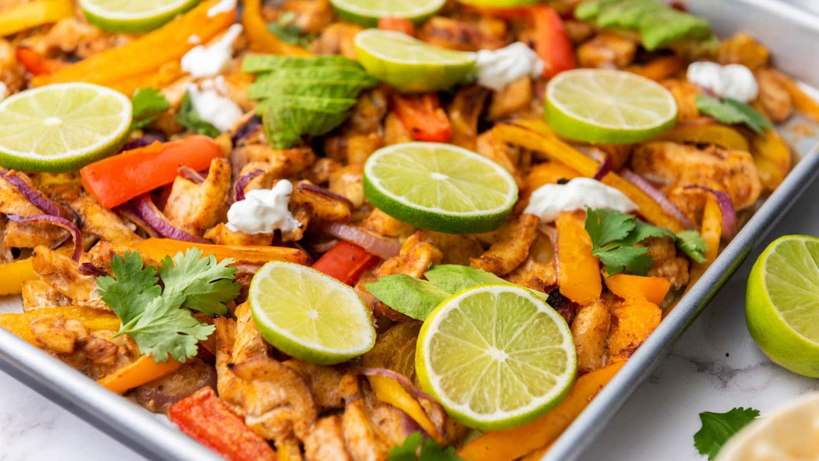 A half-viewed chicken fajitas garnished with fresh cilantro, sliced avocado and lime.