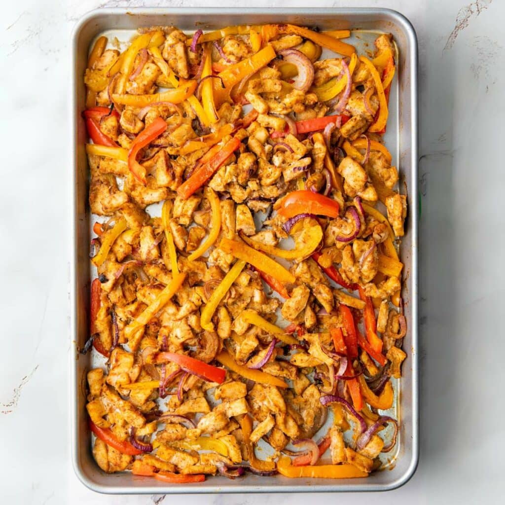 Cooked chicken with herbs and spices on a light marble surface.