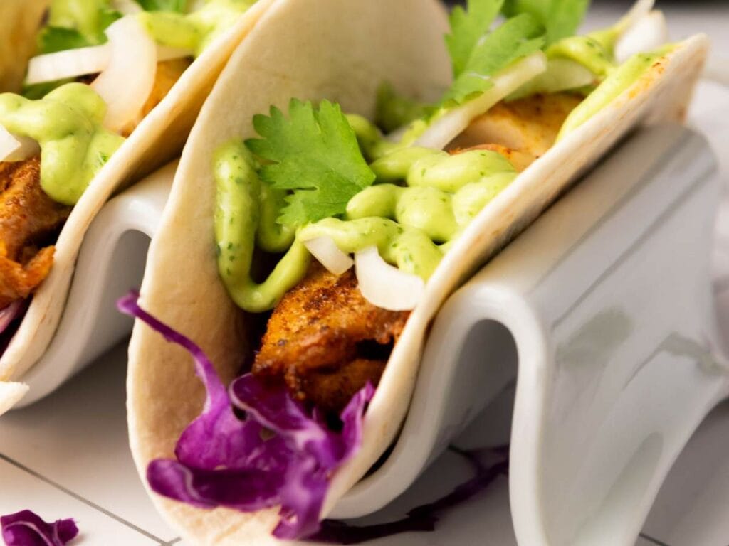Close-up of tilapia tacos in a ceramic taco holder.