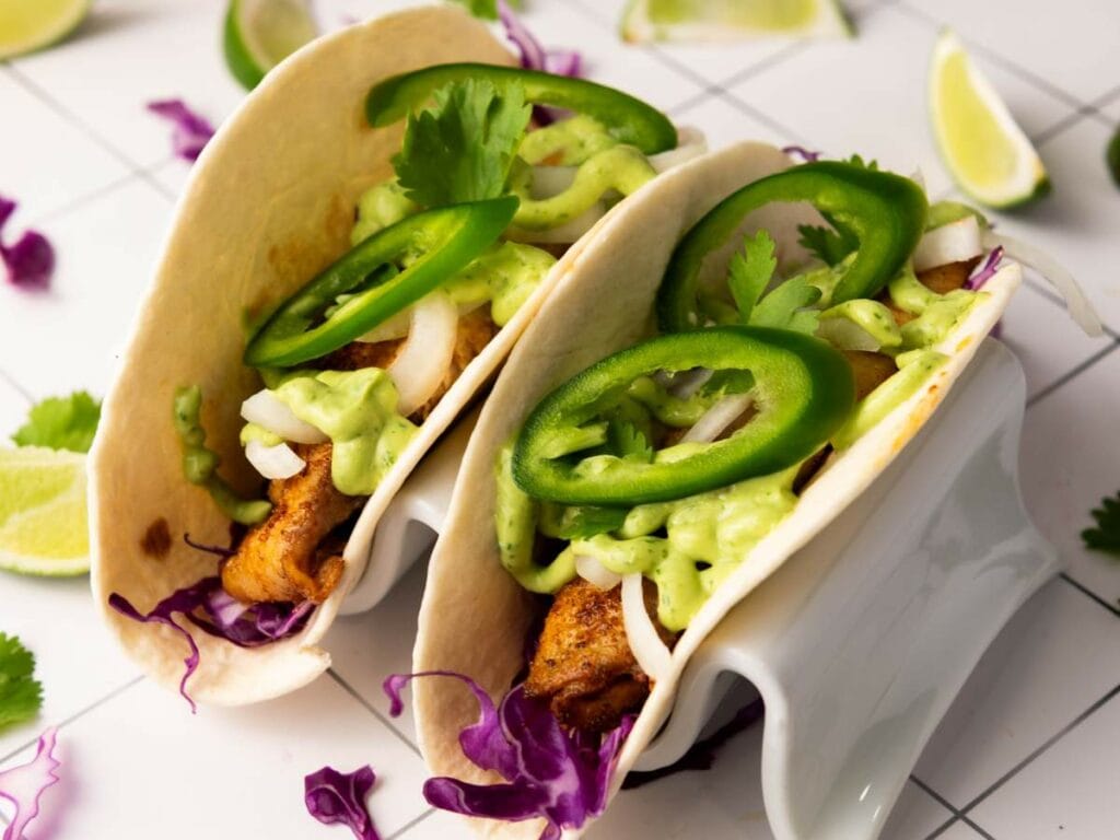 Tilapia tacos filled with grilled fish, sliced jalapeños, onions, cilantro and other ingredients.