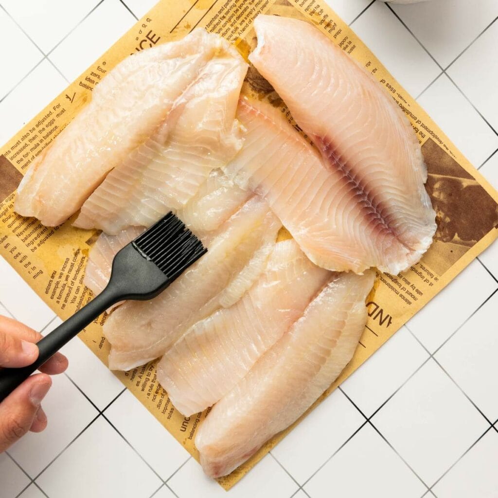 Four raw fish fillets are laid out on a piece of brown paper.