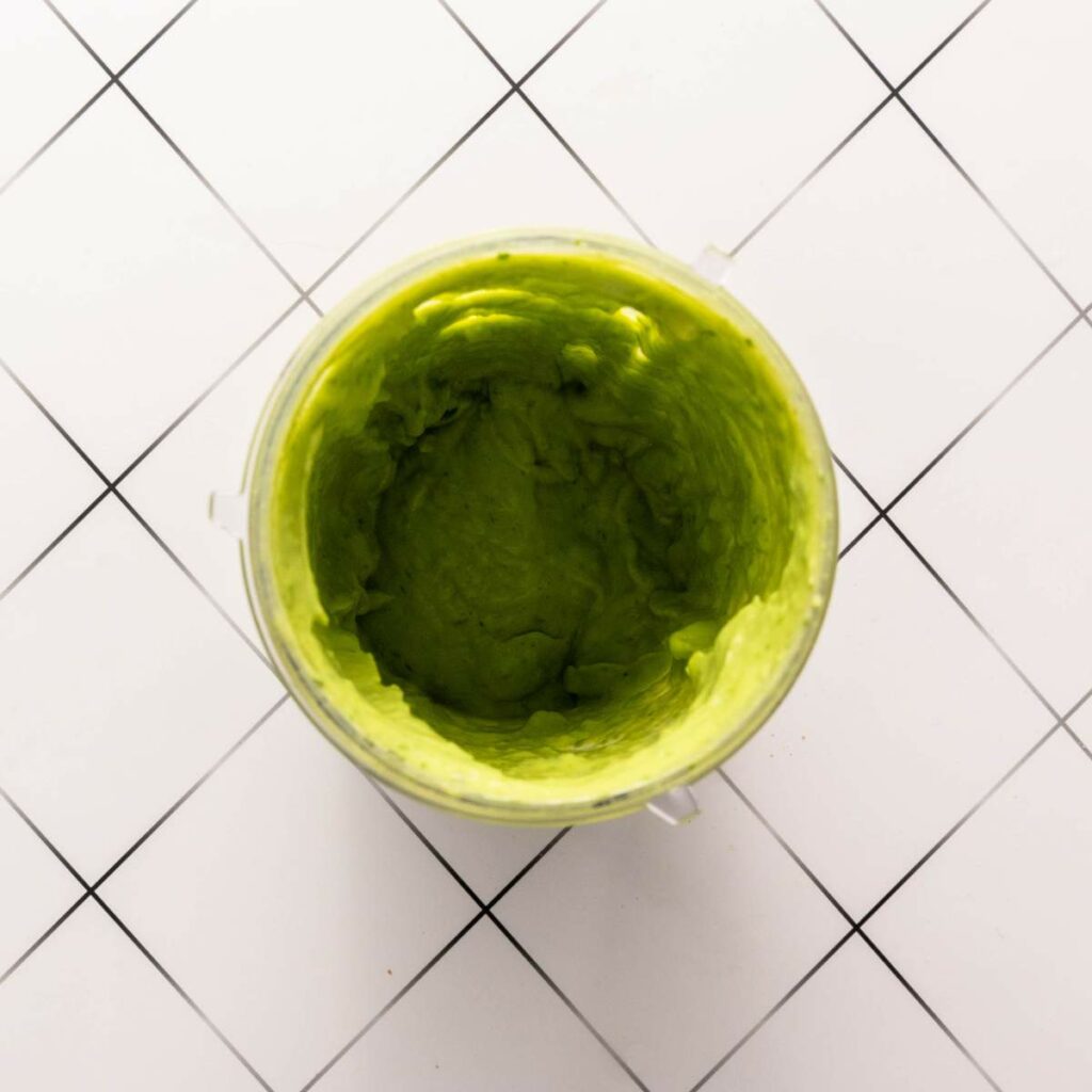 A blender container filled with smooth, green avocado mixture.