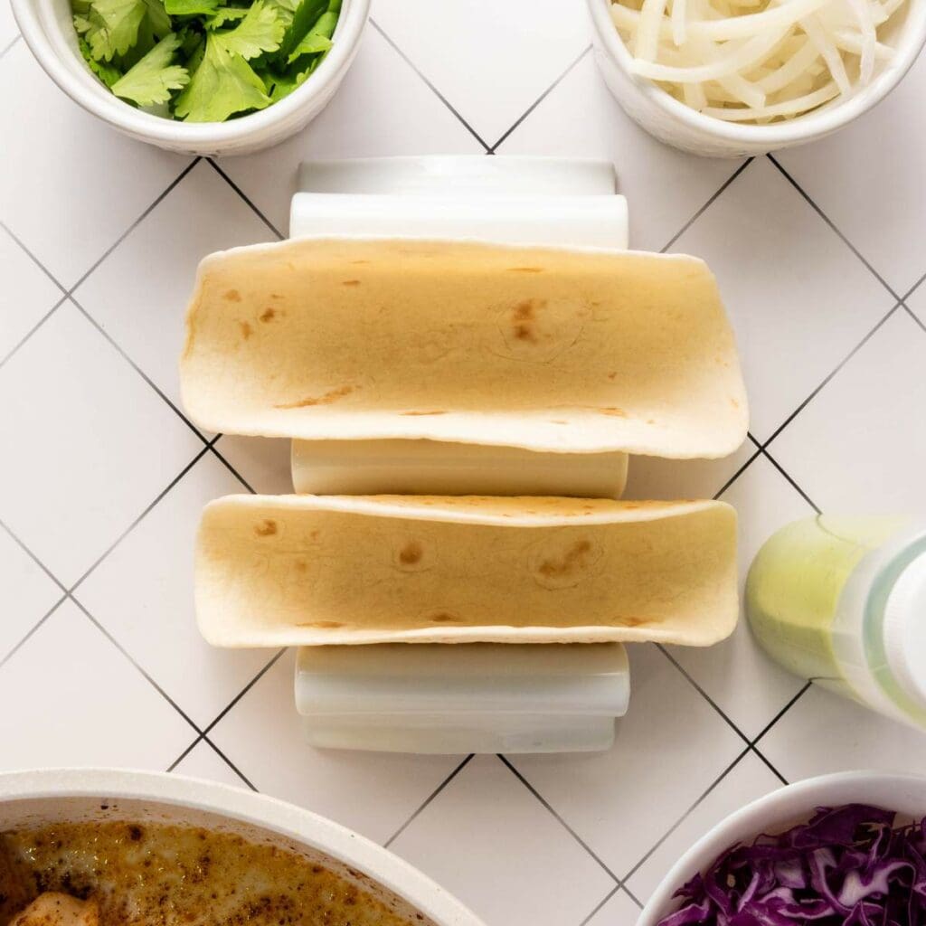 Two empty taco shells sit in a white taco holder.