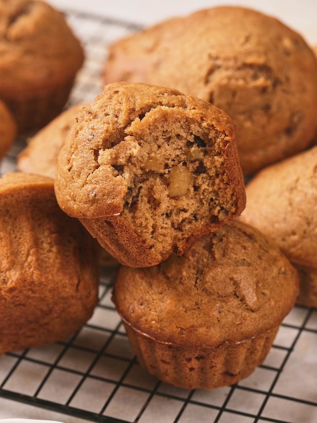 A close-up of several nut muffins on a cooling rack, with one muffin partially eaten.
