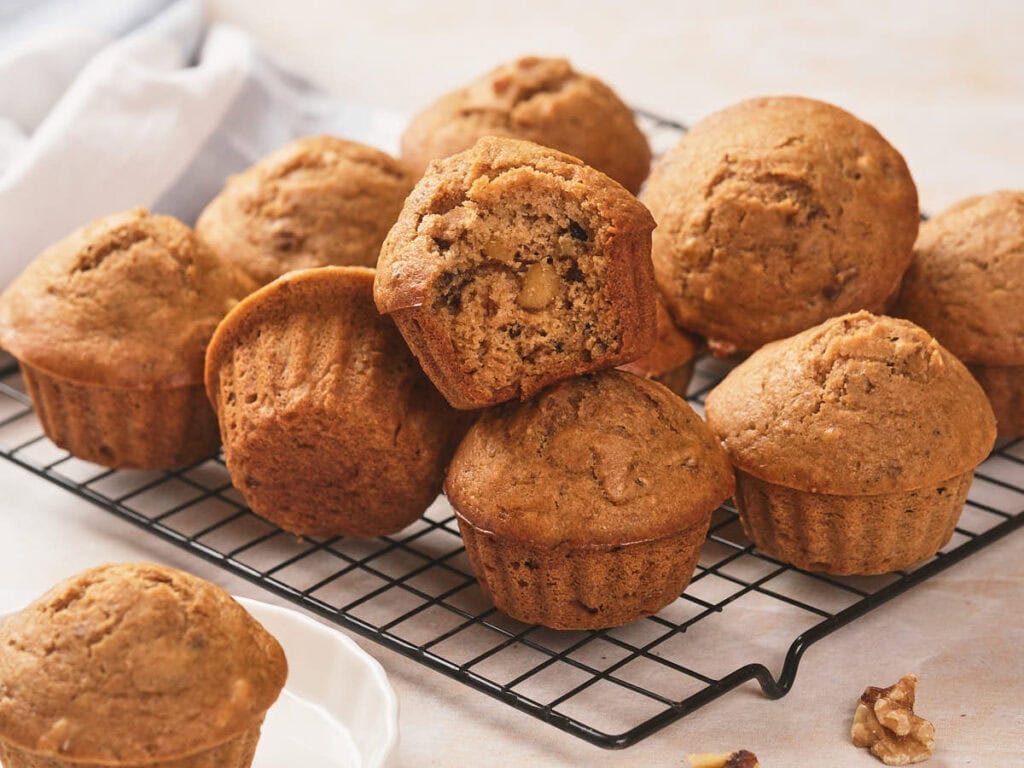 A batch of freshly baked muffins, with one muffin cut in half to show the inside texture.