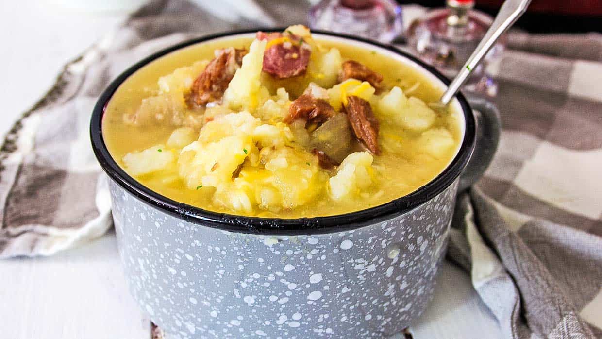Ham and Potato soup in a gray and white bowl with a spoon.
