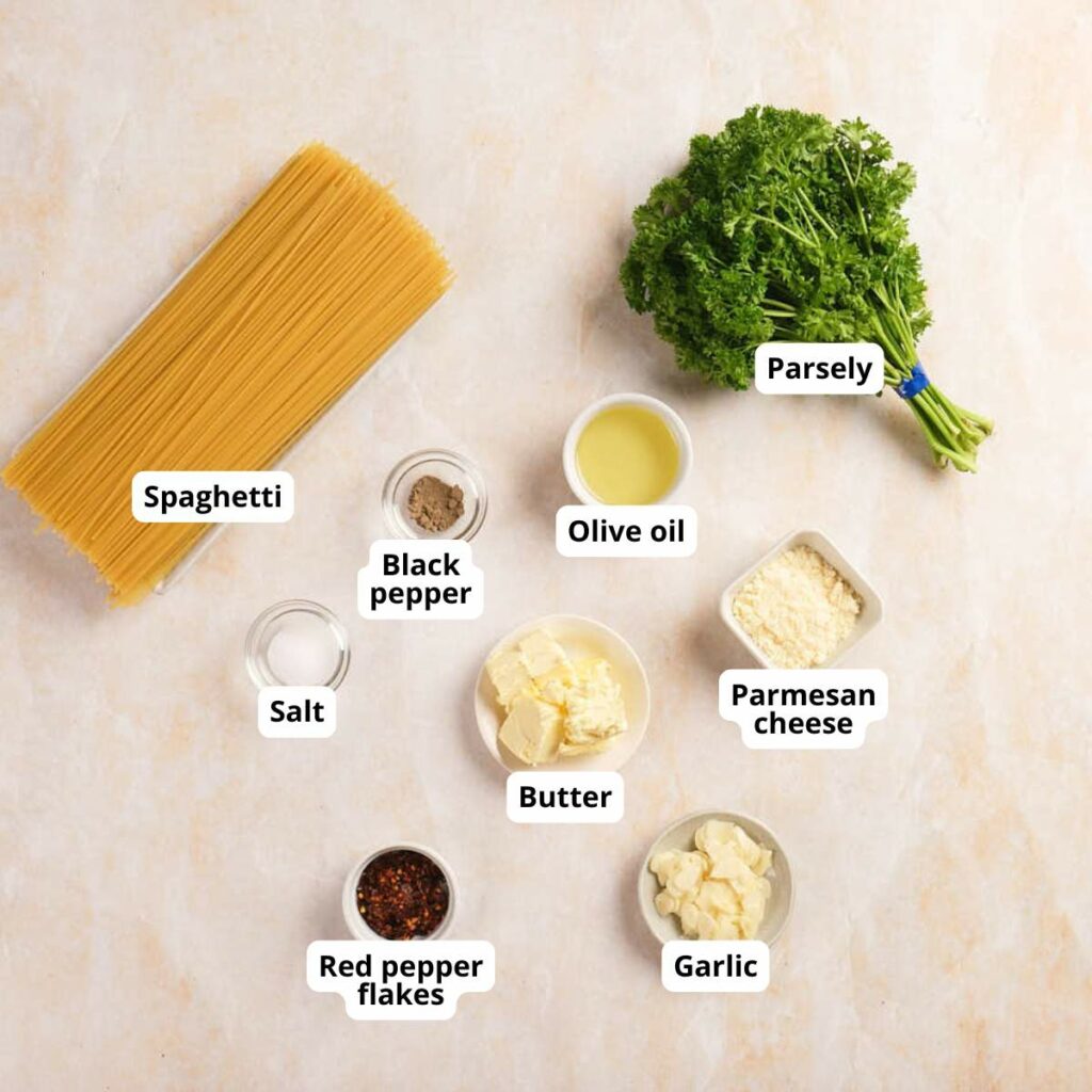 Ingredients for spaghetti aglio e olio recipe are arranged on a light surface.