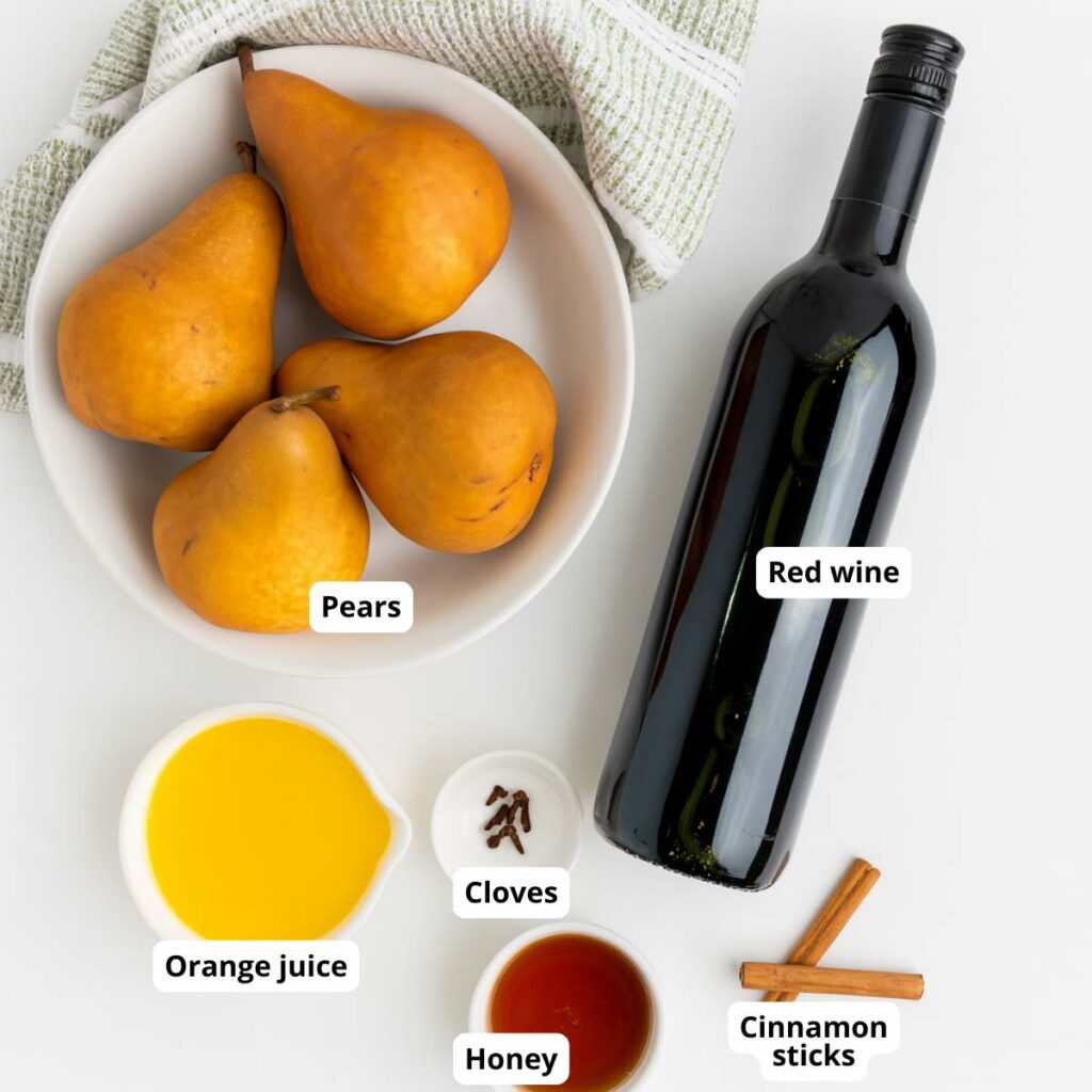 Ingredients for red wine poached pears recipe are arranged on a white surface.