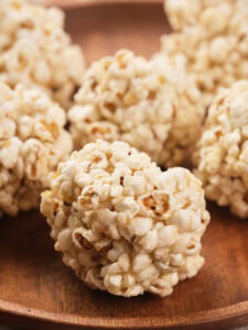 Close-up of popcorn balls arranged on a wooden plate.
