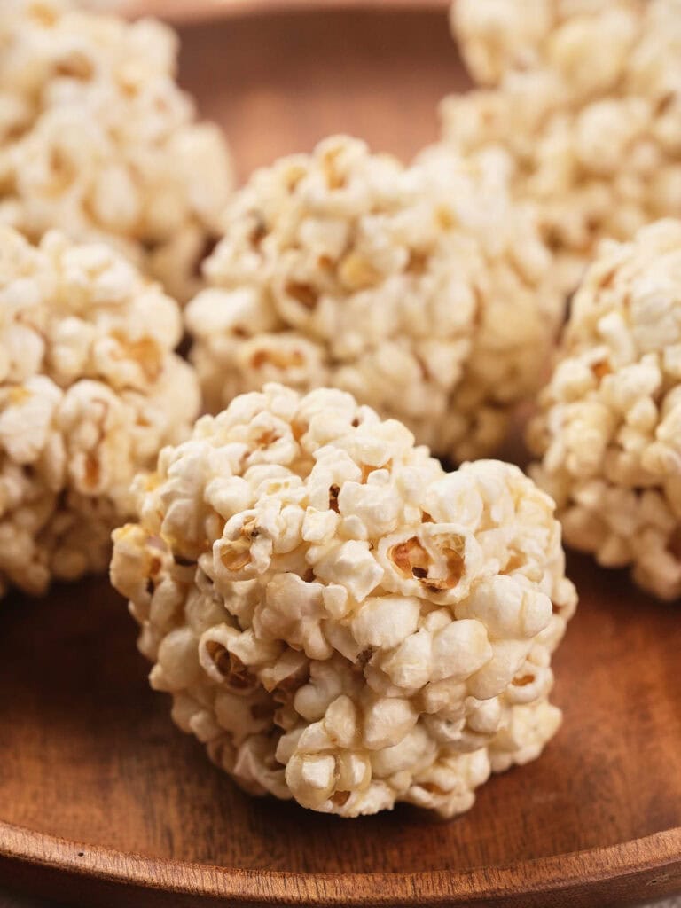 Close-up of popcorn balls arranged on a wooden plate.