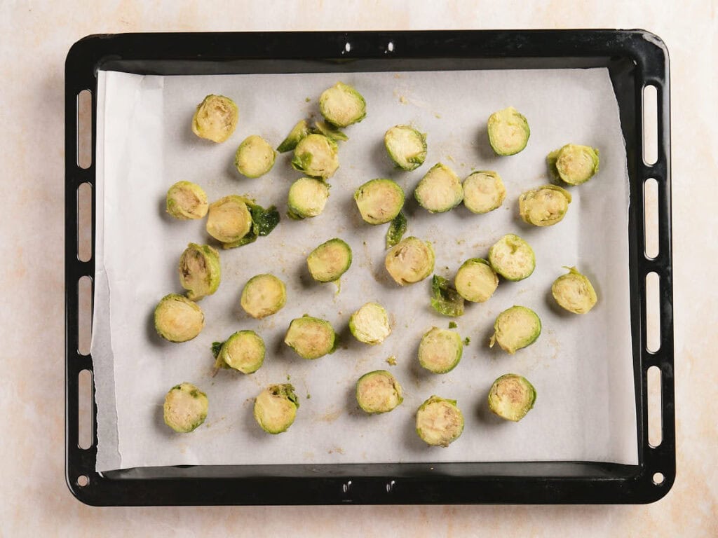 Halved Brussels sprouts arranged on a parchment-lined baking tray, ready for roasting.