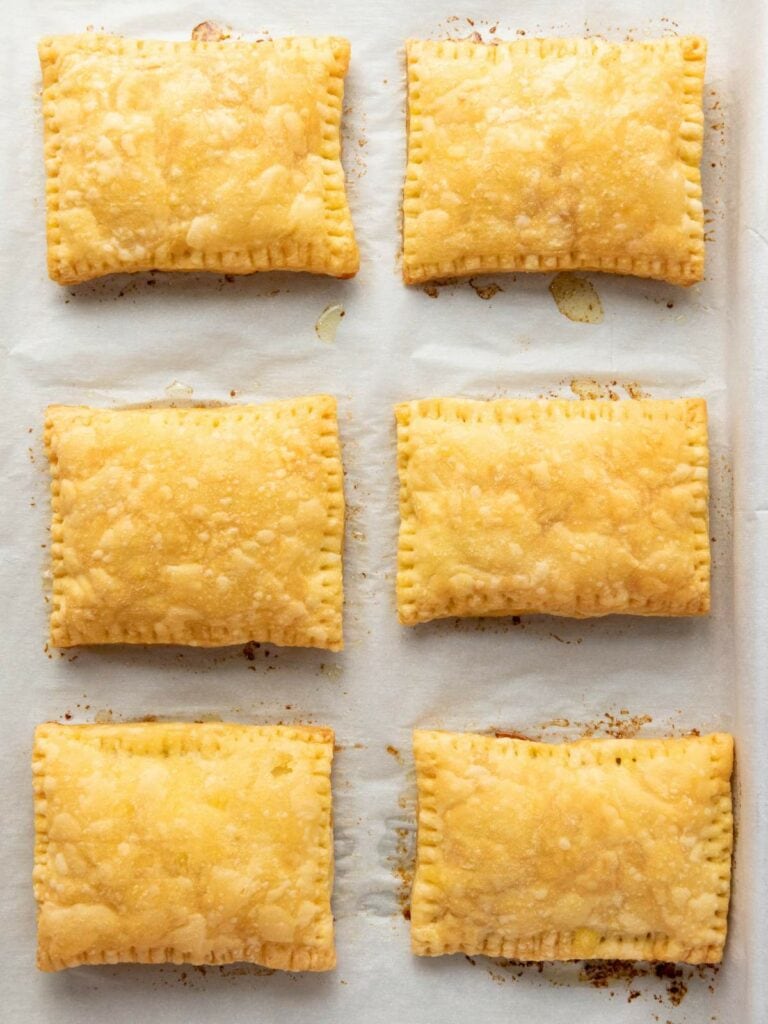Six rectangular golden-brown pastries are arranged in two rows of three on a sheet of parchment paper.