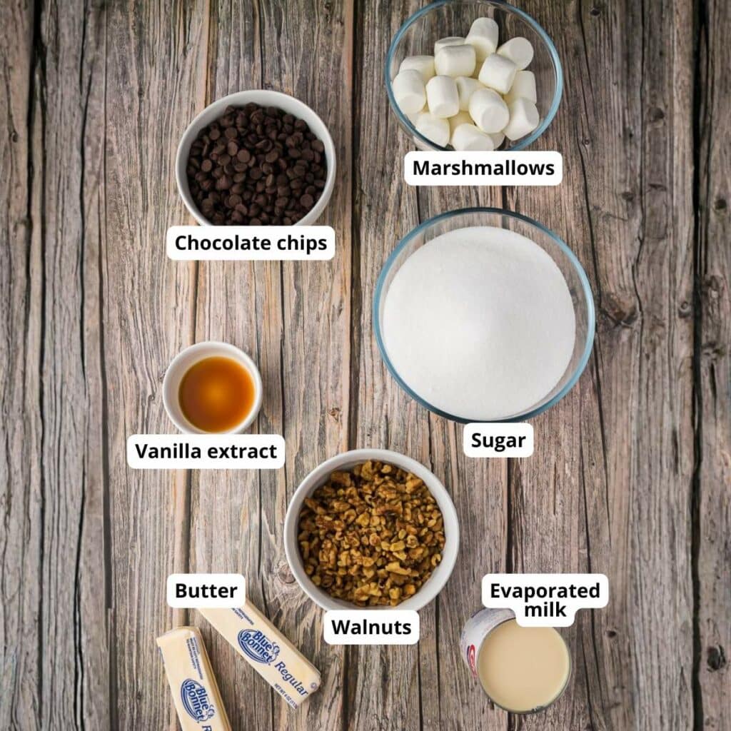 Seven labeled ingredients for a recipe—marshmallows, chocolate chips, sugar, vanilla extract, walnuts, butter, and evaporated milk.