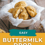 A bowl lined with a white cloth holds several buttermilk drop biscuits on a wooden table.