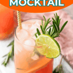 A glass of grapefruit mocktail with ice, lime slice, rosemary garnish, and a striped straw, placed on a marble surface.