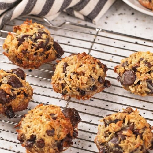Magic cookies cooling on a wire rack, with a striped kitchen towel and part of a baking pan in the background.