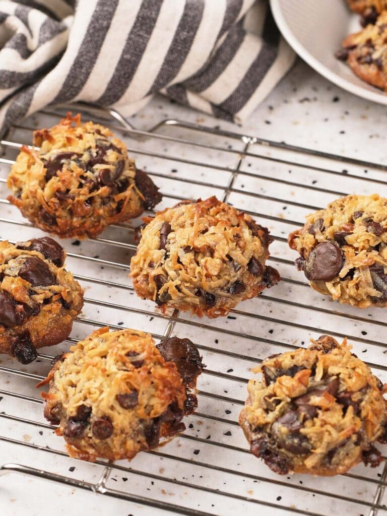 Magic cookies cooling on a wire rack, with a striped kitchen towel and part of a baking pan in the background.