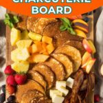 A wooden board with pancakes, fresh fruit, berries, cheese cubes, bacon, and syrup, presented as a kid-friendly breakfast charcuterie board.
