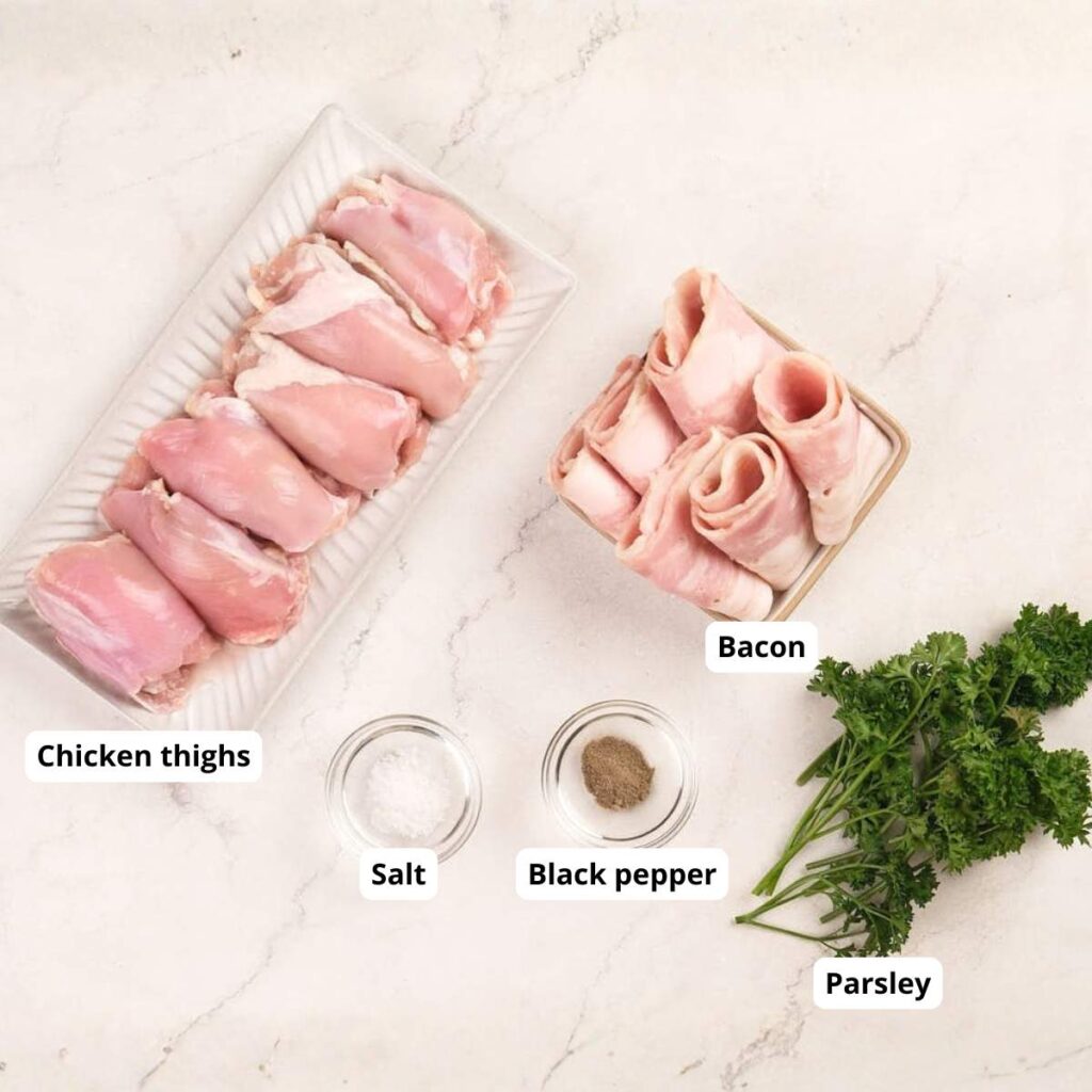 Raw chicken thighs, bacon slices, salt, black pepper, and fresh parsley arranged separately on a white marble surface. Each ingredient is labeled.