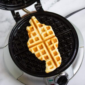 A waffle shaped like the U.S. state of Tennessee sits on a round waffle maker.
