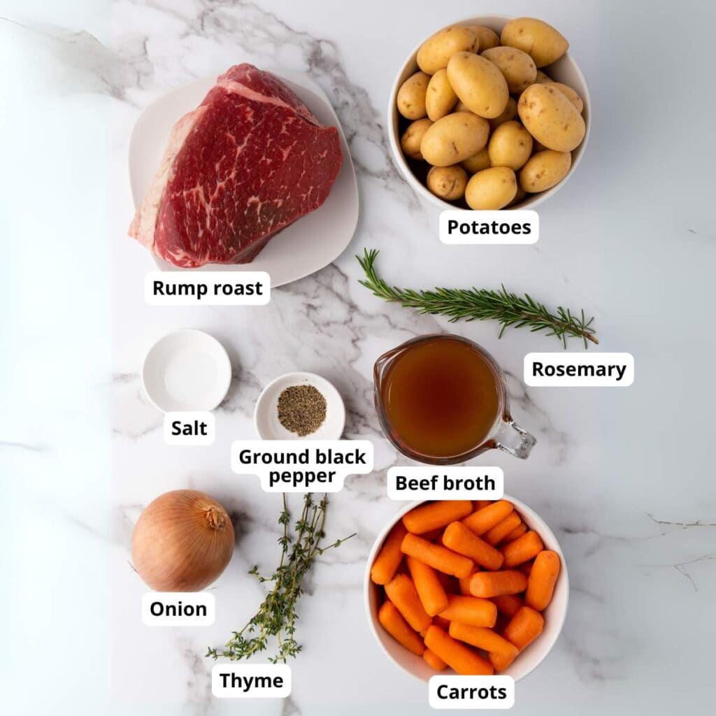 Top-down view of ingredients for a pot roast, including rump roast, potatoes, carrots, onion, beef broth, rosemary, thyme, salt, and ground black pepper on a marble surface.
