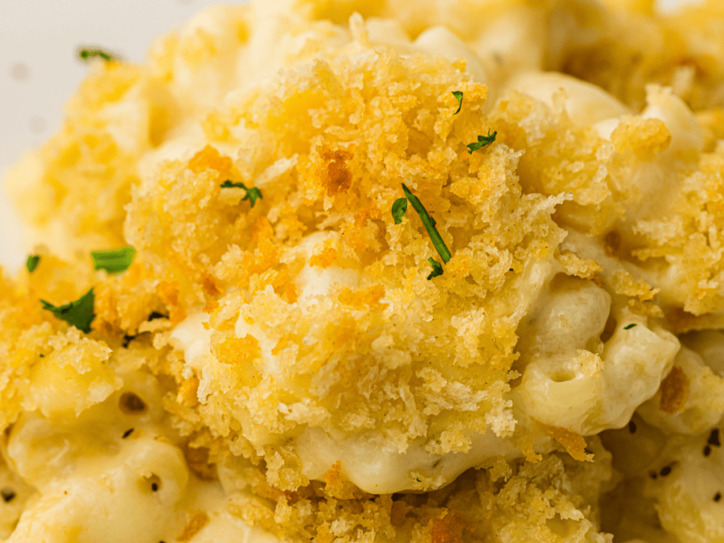 Close-up of baked macaroni and cheese topped with golden brown breadcrumbs and garnished with small pieces of parsley.