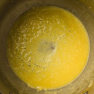 A metal mixing bowl containing a smooth, yellow batter with small bubbles on the surface.
