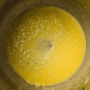 A metal mixing bowl containing a smooth, yellow batter with small bubbles on the surface.