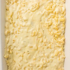 Close-up of creamy macaroni and cheese in a white rectangular baking dish, with cheese sauce covering the pasta.