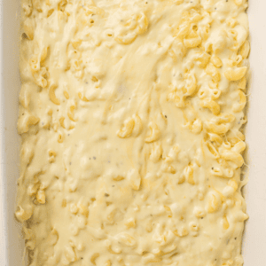Close-up of creamy macaroni and cheese in a white rectangular baking dish, with cheese sauce covering the pasta.