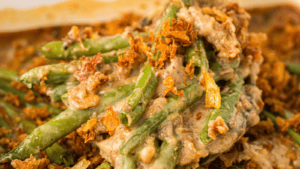 Close-up of a green bean casserole topped with mushroom, creamy sauce, and crispy fried onions.