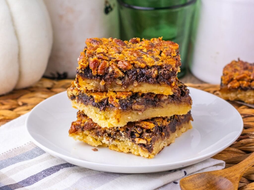 A stack of three pecan chocolate bars on a white plate.