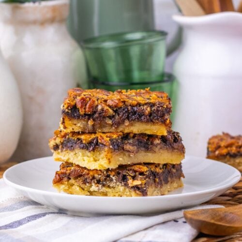 A stack of three pecan pie bars on a white plate.