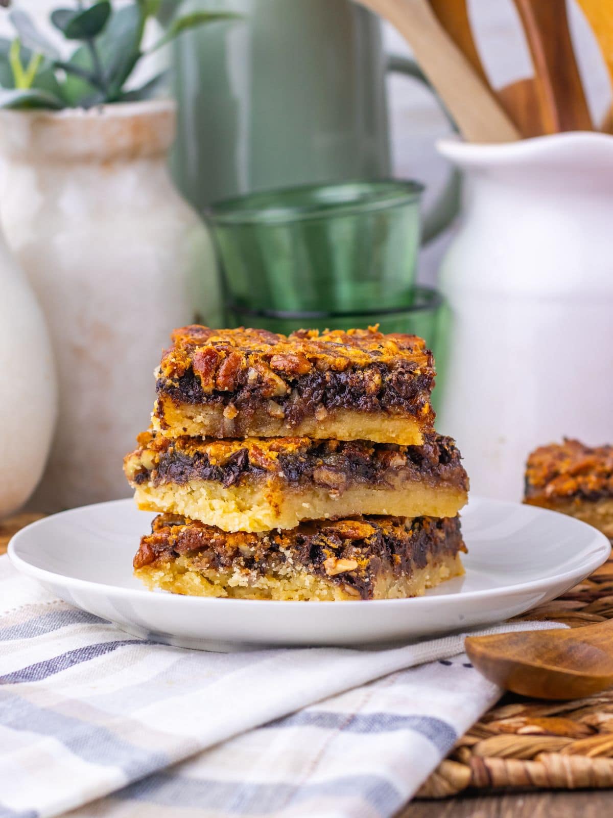 A stack of three pecan pie bars on a white plate.