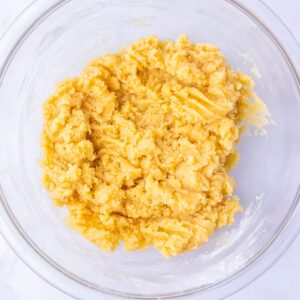A thick, yellow cookie dough mixture in a clear glass bowl.