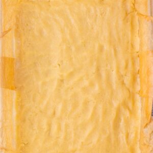 A rectangular slab of light yellow baked goods lined with parchment paper.