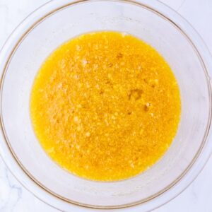 A glass bowl containing a yellow liquid mixture with fine bits of ingredients.