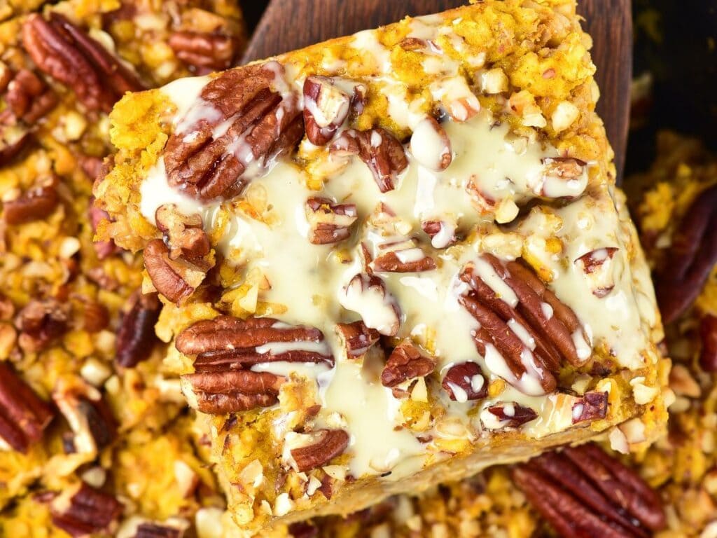 Square piece of pumpkin oat bar topped with pecans and a white glaze.