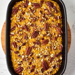 A rectangular pan of baked pumpkin bread topped with pecan halves and chopped nuts.