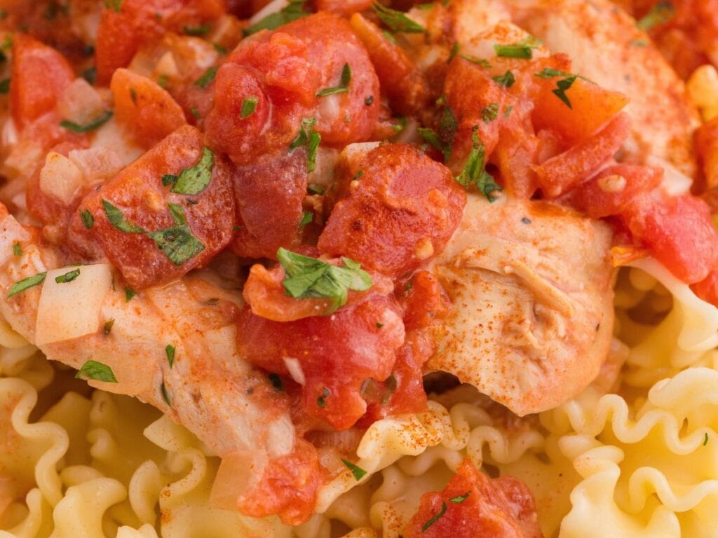 Chicken breast topped with diced tomatoes and herbs, served over ruffled pasta.