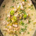 Creamy white chicken chili with white beans, corn, and sliced jalapeños in a slow cooker.