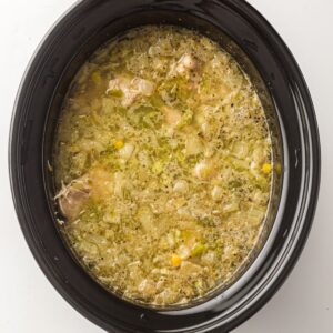 Chicken and vegetable soup simmering in a slow cooker.