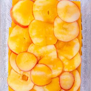 Thinly sliced peaches arranged in a glass baking dish.